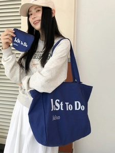 Deep blue canvas tote bag and coin purse set featuring white lettering on a casual model