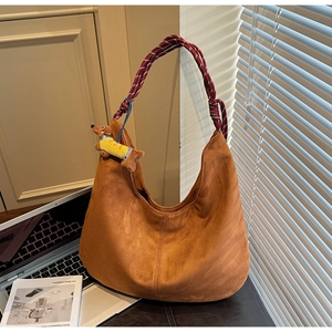Detail of brown suede hobo bag with red braided rope handle and yellow puppy charm
