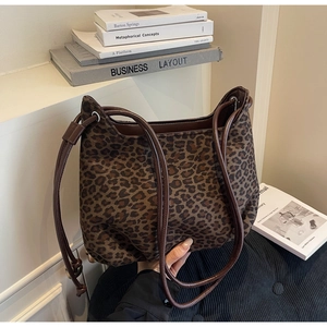 Detail shot of leopard print canvas underarm bag with dark brown leather straps