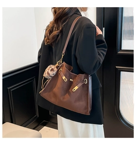 Brown suede tote bag detail with gold hardware and leopard print pompom on model