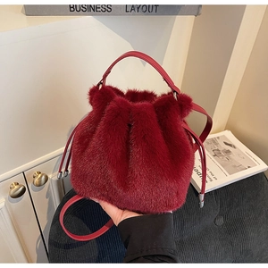 Detailed view of red plush bucket bag with leather handle and drawstring closure