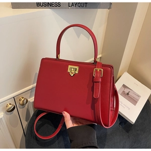 Detail of red vintage handbag featuring a gold metal twist lock and textured leather