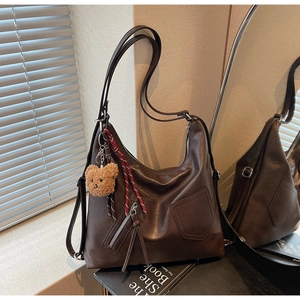 Detail of a brown vintage tote bag with functional front zipper and cute bear pendant