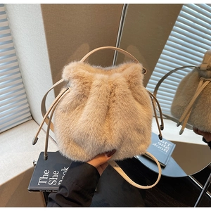 Close-up of soft beige plush bucket bag with drawstring detail and fluffy fur texture