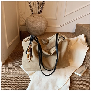 Detail of vintage khaki tote bag with wooden bead tassel charm on indoor stairs