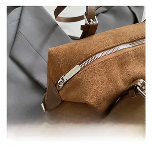 Detailed macro view of brown suede tote bag with silver zipper and leather strap buckles