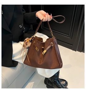 Detail view of coffee brown suede tote bag with leopard plush charm and gold hardware
