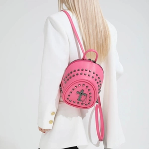 Macro shot of hot pink mini backpack with silver rivets and metallic cross charm detail