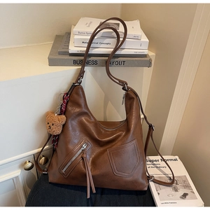 Detailed view of brown vintage leather hobo bag with side zipper and plush bear charm