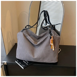 Detail view of large grey canvas tote bag with wooden bead charm and black leather handles