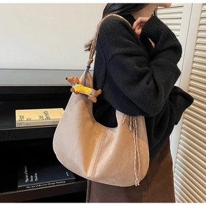Detail of light brown suede Hobo bag with woven handle and cute dachshund doll charm