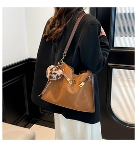 Brown suede tote bag with leopard charm shown on model in a minimalist setting