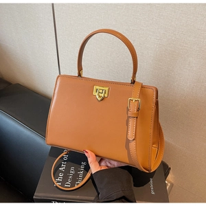 Close-up of camel leather handbag with gold twist lock and adjustable shoulder strap