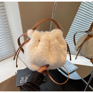 Detail of plush cream bucket bag featuring brown leather drawstring and textured faux fur