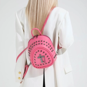 Rear view of a pink mini studded backpack with silver cross charm on a white blazer