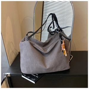 Close-up of a vintage grey canvas tote bag with wooden bead charm and black straps