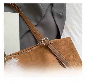 Detail of adjustable leather strap with silver buckle on brown suede tote bag