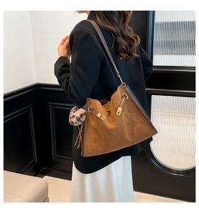 Side view of a vintage tan tote bag with leopard print charm and golden hardware detail
