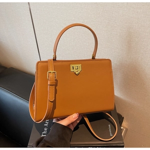 Détail du sac à main en cuir caramel avec fermoir doré rotatif et poignée ronde
