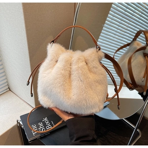 Detail of plush faux fur bucket bag featuring brown leather drawstring and soft cream texture