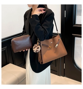 Detail of tan tote bag with brown pouch featuring tassel drawstrings and fuzzy pom pom