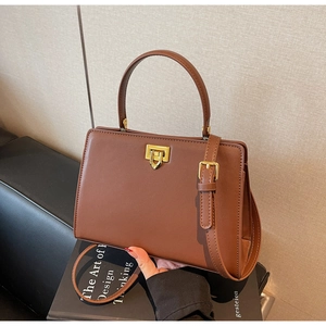 Detail of vintage brown leather handbag featuring a golden square twist lock and top handle