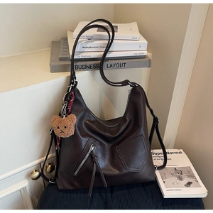 Detail of vintage brown PU leather tote bag with asymmetric pockets and teddy bear pendant
