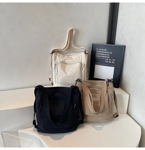 Three large capacity tote bags in black, beige, and khaki on minimalist steps