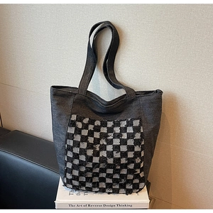 Détail d'un grand sac cabas en jean gris avec poche en damier et bords effilochés
