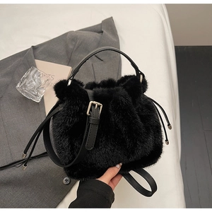 Detail of plush black faux fur bucket bag with leather handle and drawstring closure