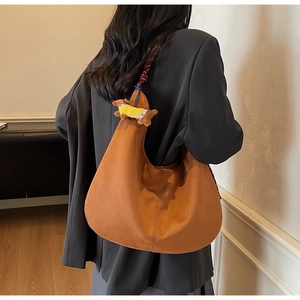 Detail of caramel hobo bag featuring a cute dachshund plush charm and suede texture