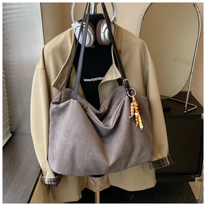 Detail of grey canvas tote bag with ethnic wooden bead charm on a clothing rack