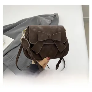 Detail of dark brown matte PU crossbody bag with large bow and woven handle