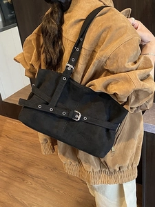 Black suede tote bag with adjustable buckle straps and metal eyelets for a chic urban look