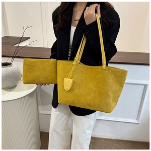 Detail view of mustard yellow suede tote bag with matching zippered pouch and leather charm