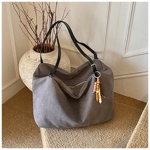 Detailed shot of dark gray canvas tote bag with vintage wooden bead charm and black strap