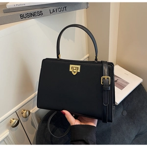 Detail of black leather handbag with premium gold metal lock in a minimalist setting