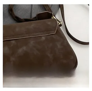 Macro shot of dark brown faux suede material and gold metal buckle on a square bag