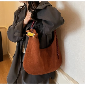 Close-up of brown suede hobo bag with braided rope strap and cute dachshund pendant