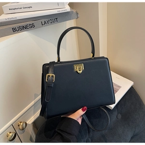 Détail d'un sac cabas noir mat avec fermoir rotatif doré et bandoulière ajustable