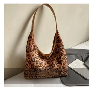 Detail of leopard print tote bag featuring brown leather straps and spacious interior design