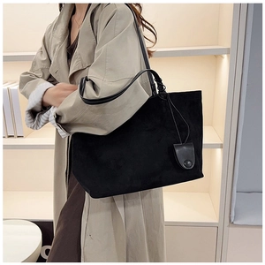 Detail of black suede tote bag styled with beige coat for autumn winter fashion look