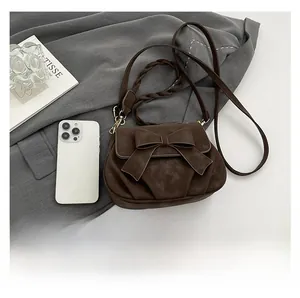 Size comparison of a dark brown bow shoulder bag next to a smartphone