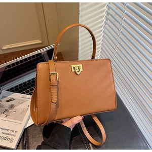Detail of a brown structured handbag with golden twist-lock and smooth faux leather
