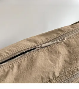 Close-up of the smooth zipper closure and textured khaki nylon fabric on the tote bag