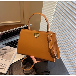 Detail of caramel brown handbag featuring gold twist lock and a sleek curved handle
