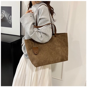 Detail view of large brown suede tote bag with leather strap on a model outfit