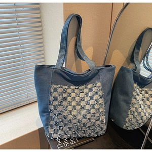 Détail du motif à carreaux effiloché sur un sac cabas en denim bleu de style urbain