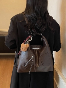 Retro brown faux leather tote bag with bear charm and asymmetric pockets shown on model
