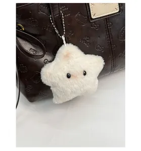 Close-up of white star-shaped fluffy plush charm attached to a dark leather tote bag